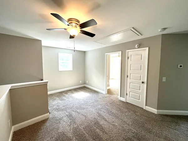 a view of an empty room with window and a ceiling fan