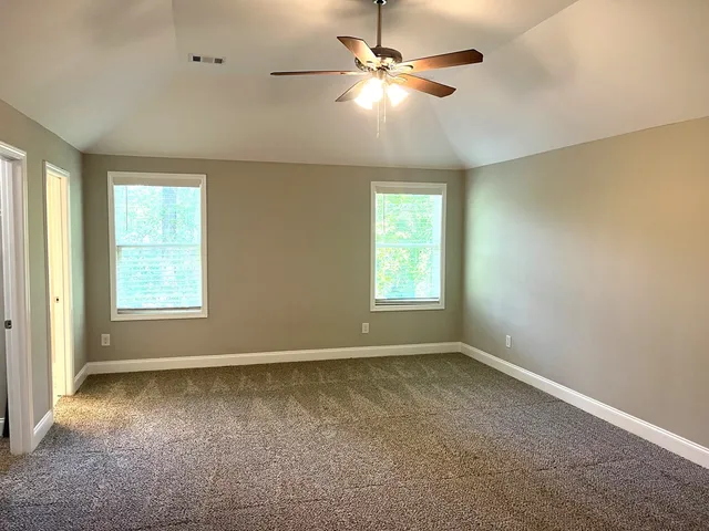 an empty room with windows and fan
