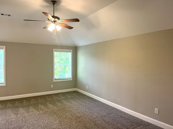 an empty room with a window and a chandelier fan