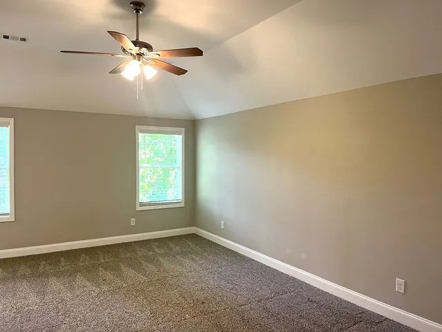 an empty room with a window and a chandelier fan