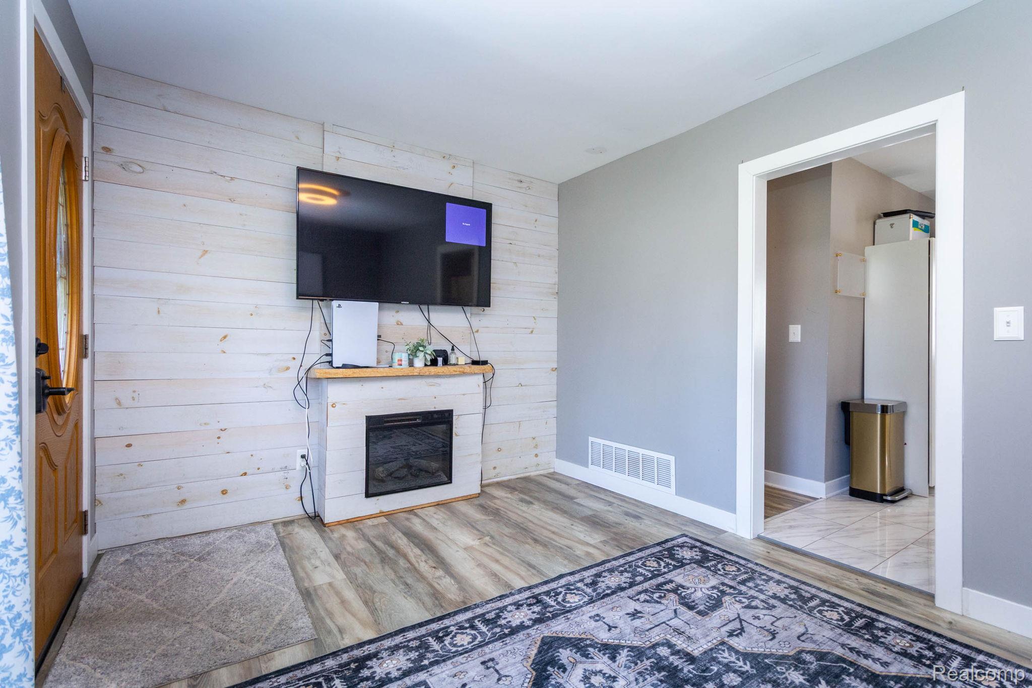 2559 Harrison Avenue Rochester, MI 48307 - Photo 10 of 32 Living area featuring wood-finish flooring and an electric fireplace with a wood mantle, entry to kitchen