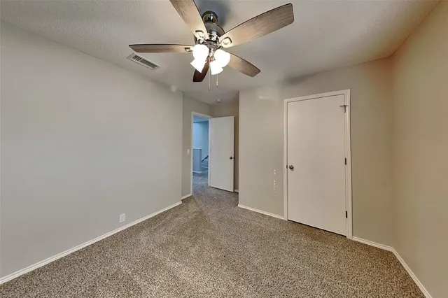 a view of an empty room with a chandelier fan