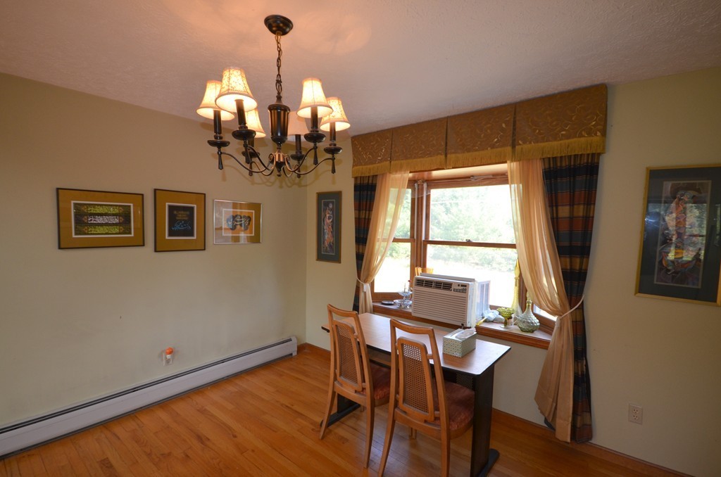 350 Warren Wright Road Belchertown, MA 01007 - Photo 13 of 30 a dining room with wooden floor a chandelier a wooden table and chairs