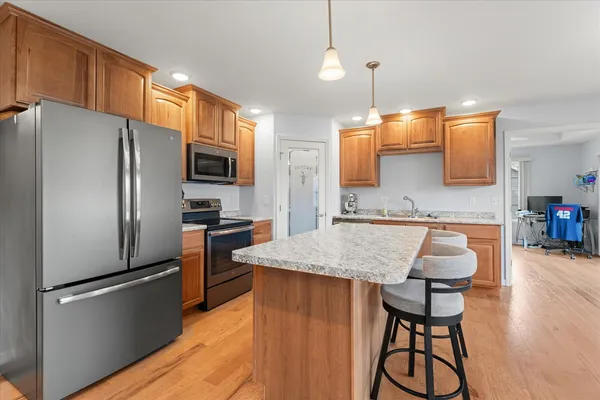 a kitchen with stainless steel appliances granite countertop a refrigerator a sink dishwasher a stove with chairs and wooden floor