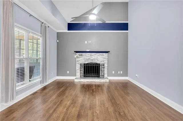 a view of an empty room with wooden floor fireplace and a window