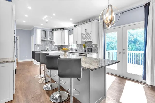 a kitchen with stainless steel appliances kitchen island granite countertop a table chairs and a chandelier