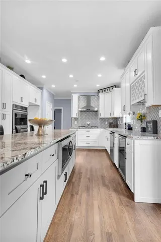 a large kitchen with stainless steel appliances granite countertop a lot of counter space and wooden floors