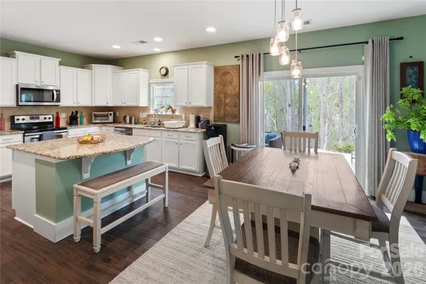 a kitchen with stainless steel appliances granite countertop a stove a refrigerator a kitchen island and chairs with wooden floor