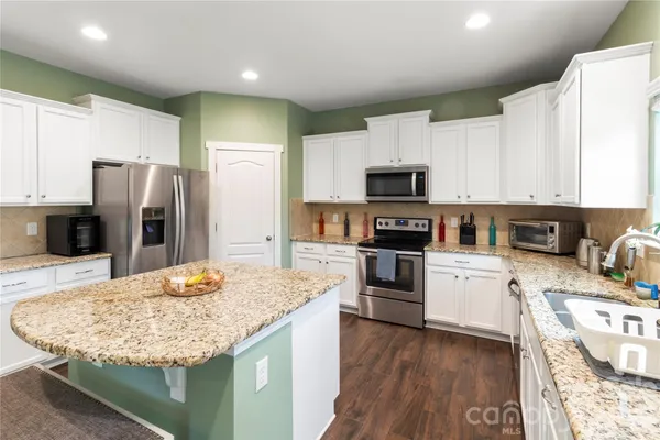 a kitchen with stainless steel appliances kitchen island granite countertop a refrigerator stove microwave and sink