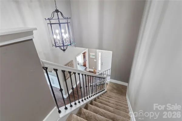 a view of staircase with railing and pendant lights