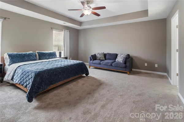 a bedroom with a bed couch chandelier and a window