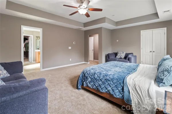 a spacious bedroom with a large bed and ceiling fan