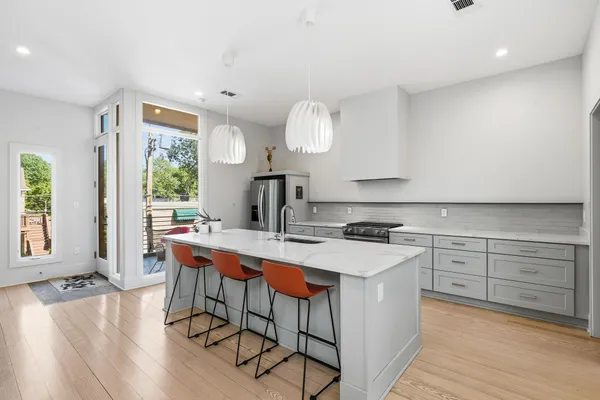 a kitchen with a stove a sink dishwasher white cabinets and a dining table with wooden floor