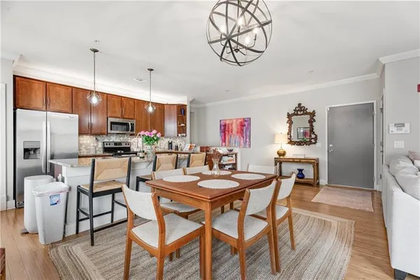 a kitchen with stainless steel appliances a dining table chairs stove refrigerator and cabinets