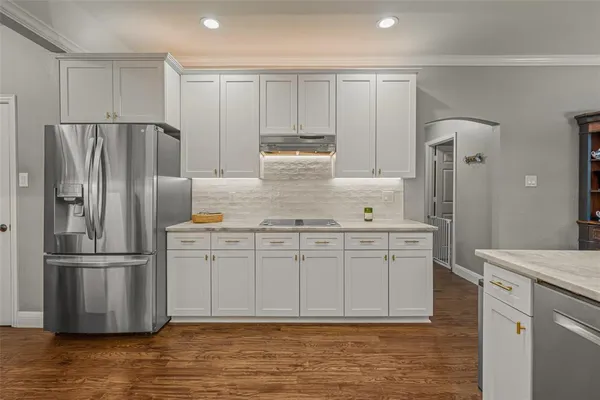 a kitchen with stainless steel appliances granite countertop a refrigerator a stove and a sink with wooden floor
