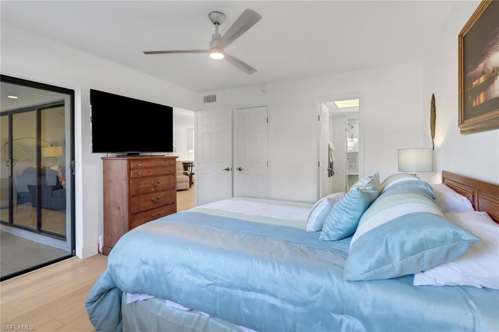 1200 Cherrystone Court, Unit A104 Naples, FL 34102 - Photo 14 of 29 Bedroom featuring access to exterior, ensuite bath, visible vents, light wood-style floors, and ceiling fan