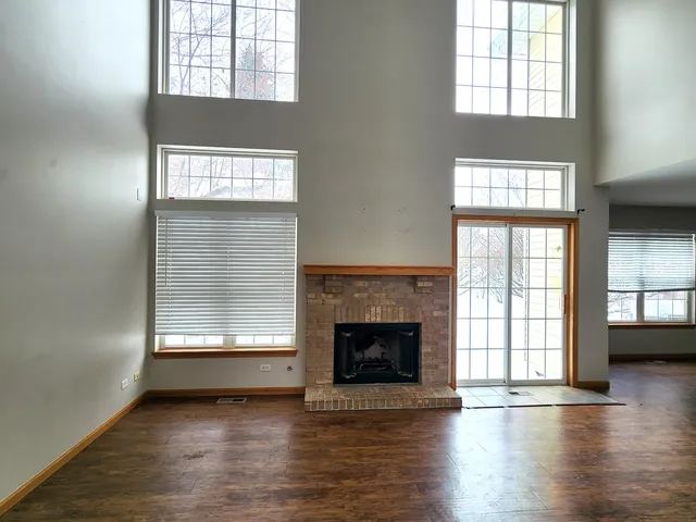 an empty room with wooden floor fireplace and windows