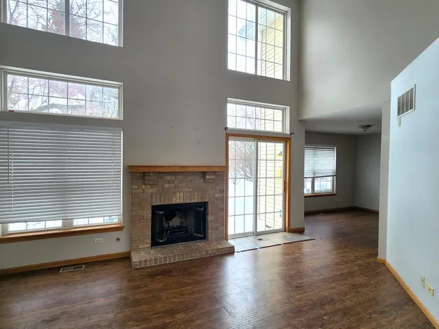an empty room with wooden floor fireplace and windows