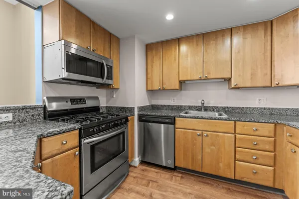 a kitchen with stainless steel appliances granite countertop a stove a sink and a microwave