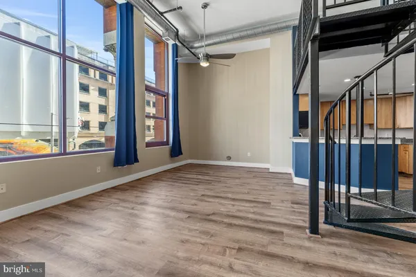 a view of an empty room with wooden floor and windows