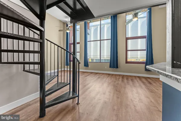 a view of an empty room with wooden floor and fan