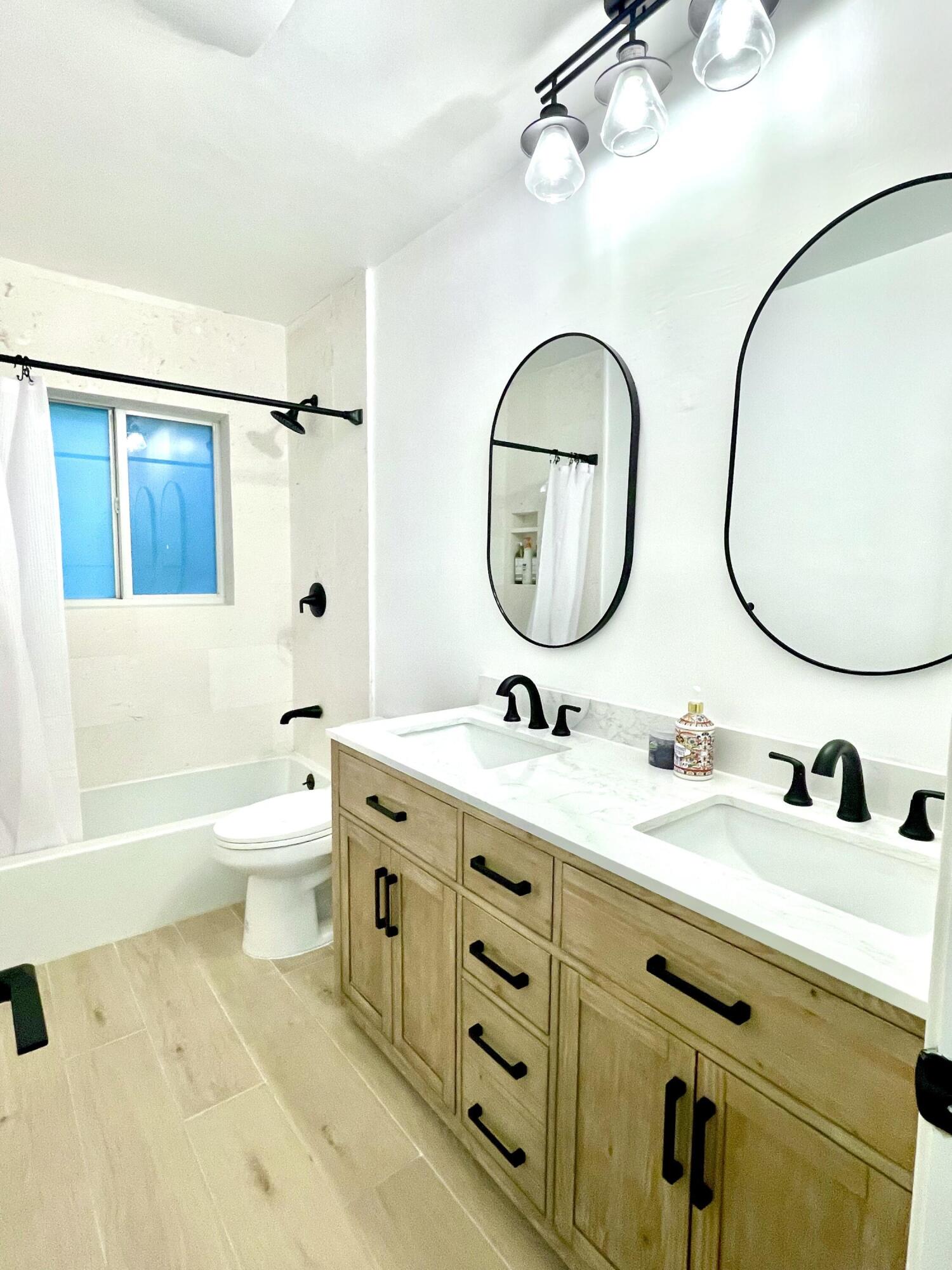 921 Northwest 7th Street Boca Raton, FL 33486 - Photo 12 of 18 a bathroom with a toilet a sink a mirror and a bathtub