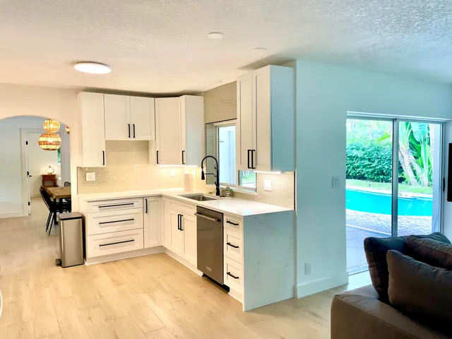 a kitchen with a stove a sink and white cabinets