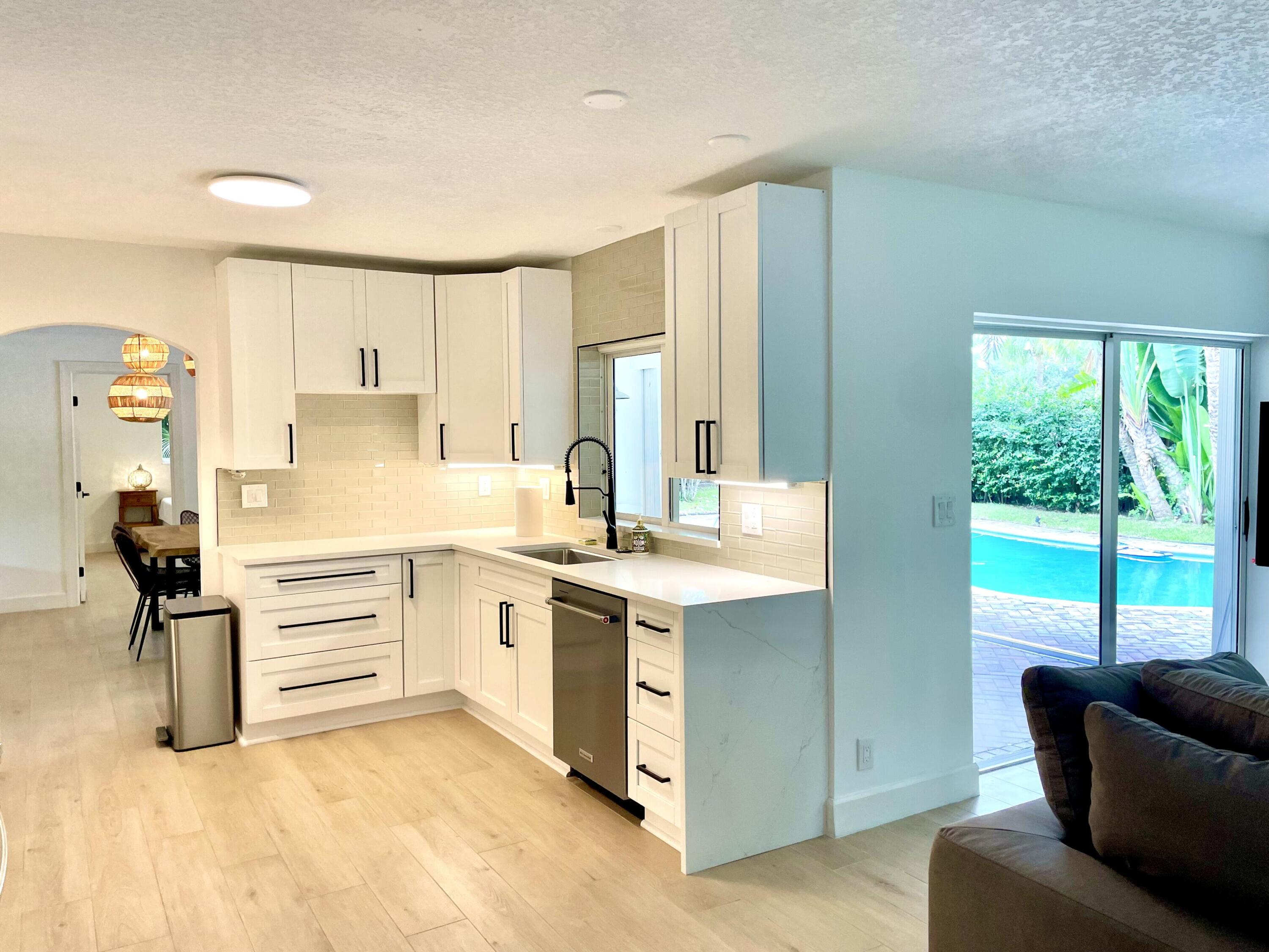 921 Northwest 7th Street Boca Raton, FL 33486 - Photo 6 of 18 a kitchen with a stove a sink and white cabinets