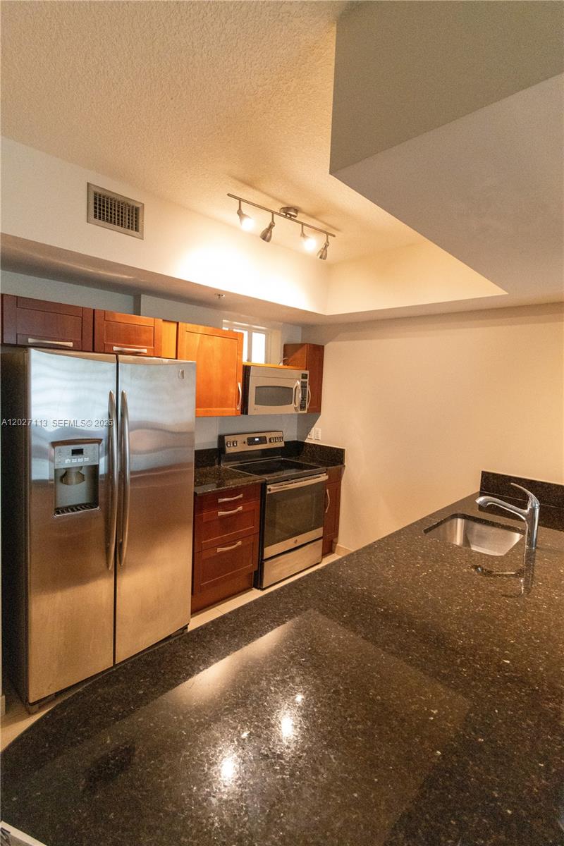7275 Southwest 90th Way, Unit 213 Miami, FL 33156 - Photo 13 of 31 a kitchen with granite countertop a refrigerator and a sink