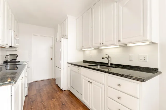 a kitchen with granite countertop a sink a stove and cabinets