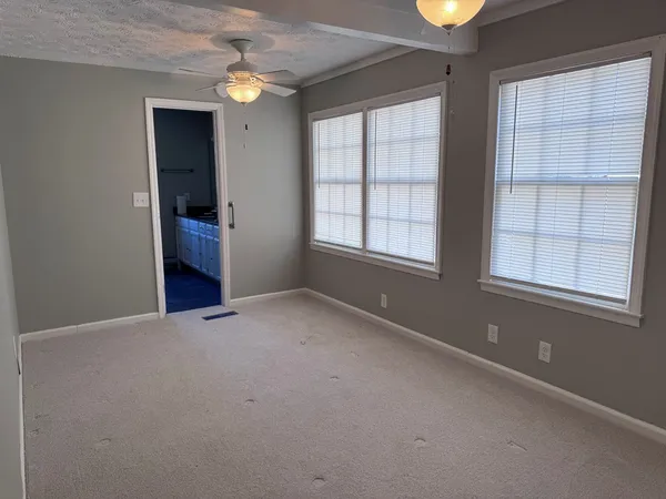 an empty room with chandelier fan and windows