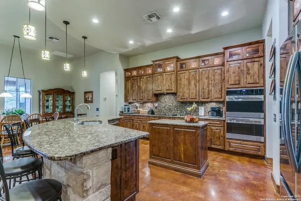 a kitchen with stainless steel appliances granite countertop a kitchen island a stove and a sink