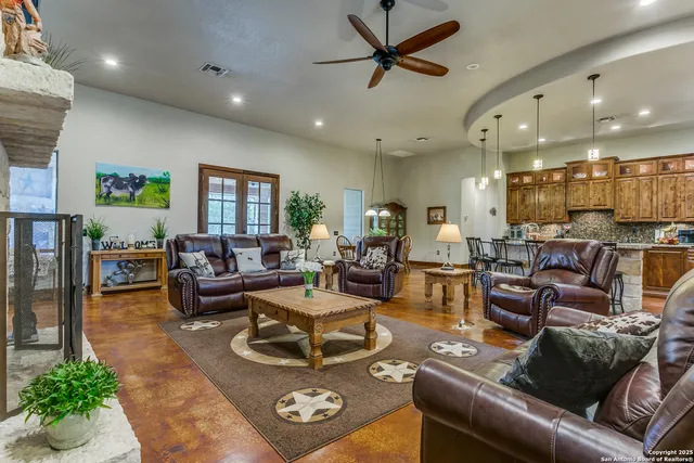 a living room with furniture kitchen view and a large window