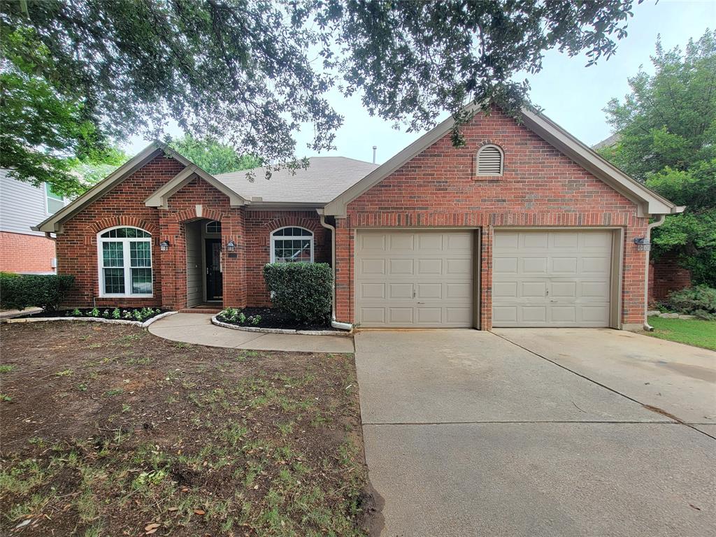 1604 Knoll Ridge Circle Corinth, TX 76210 - Photo 2 of 37 Brick exterior featuring an arched entry, a two-car garage, and a concrete driveway