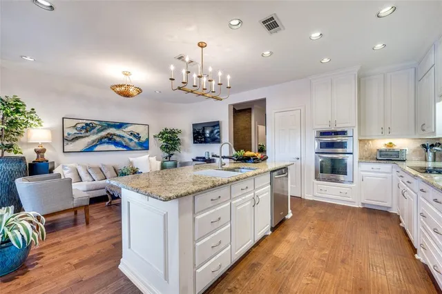 a kitchen with kitchen island granite countertop a sink cabinets and stainless steel appliances