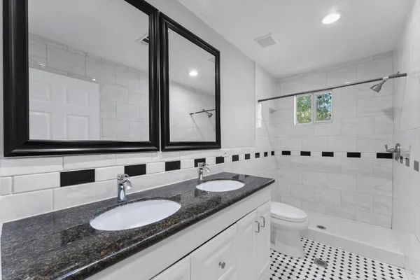 a bathroom with a granite countertop sink mirror and toilet
