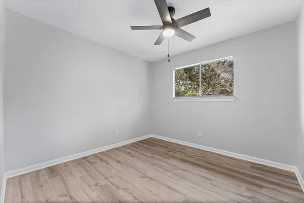 an empty room with wooden floor and ceiling fan