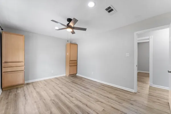a view of empty room with wooden floor and fan