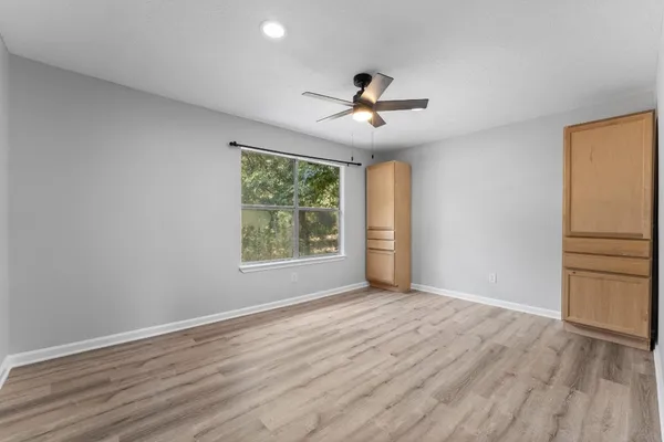 a view of empty room with wooden floor and fan