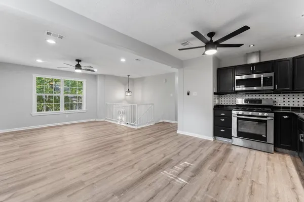 a view of kitchen with kitchen island wooden floor and stainless steel appliances