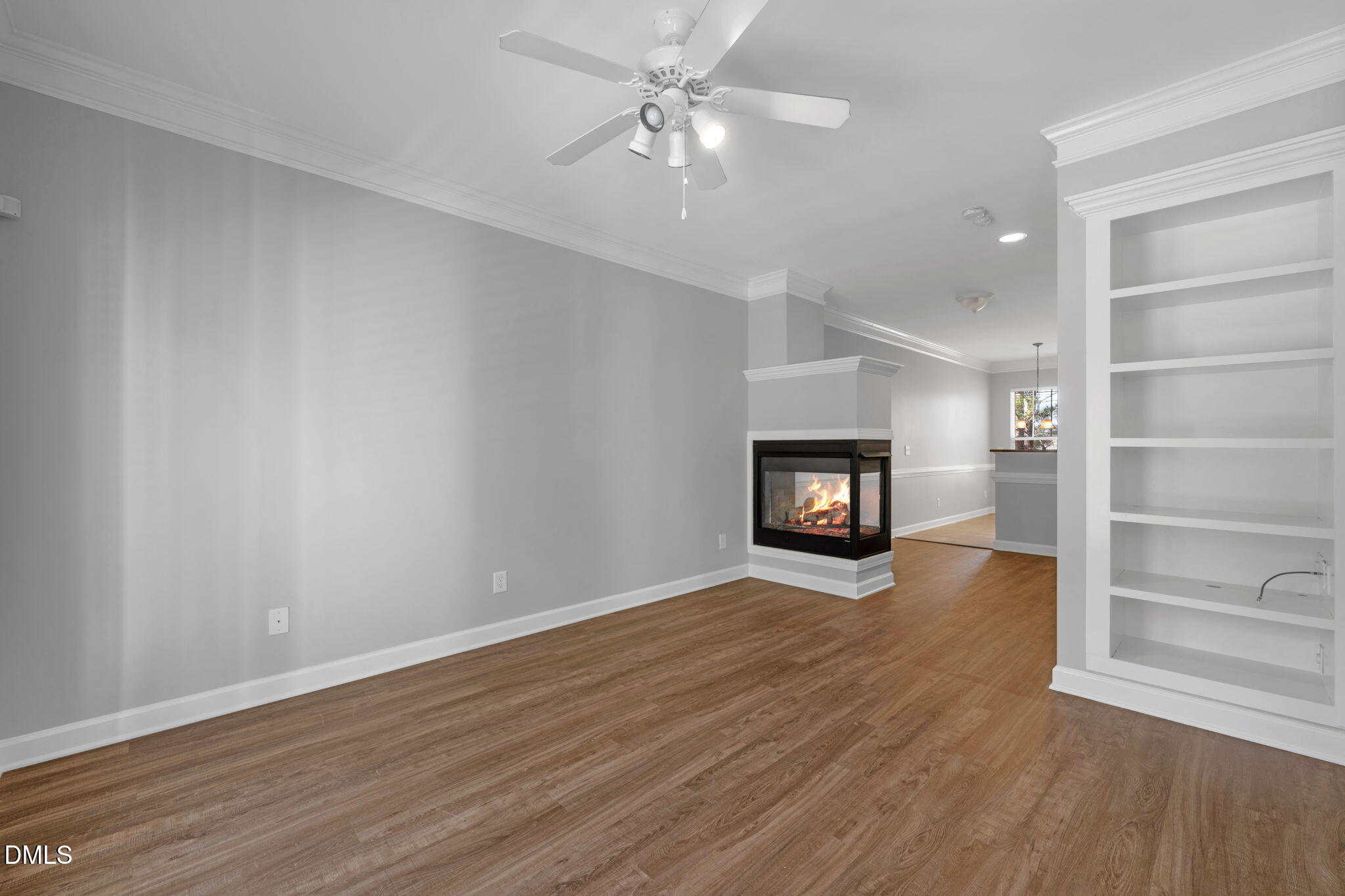 8005 Sycamore Hill Lane Raleigh, NC 27612 - Photo 19 of 31 an empty room with wooden floor a ceiling fan and fireplace