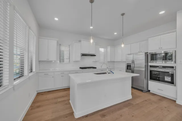 a kitchen with stainless steel appliances granite countertop a sink a stove and a refrigerator