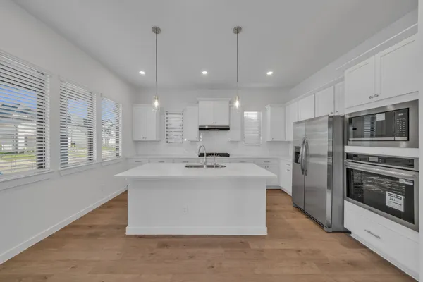 a large kitchen with kitchen island a large counter top stainless steel appliances and cabinets