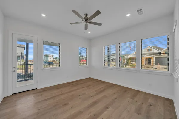 a view of an empty room with a window and wooden floor