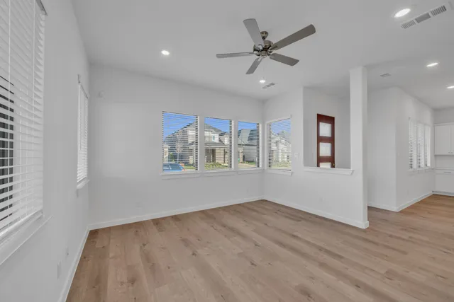 a view of empty room with wooden floor and fan