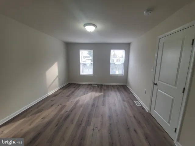 a view of an empty room with wooden floor and window