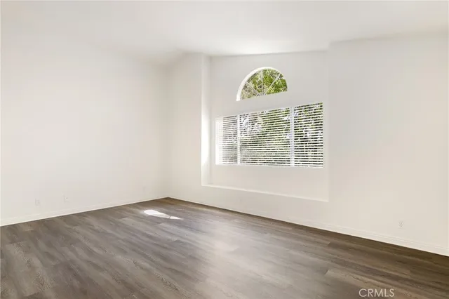 an empty room with wooden floor and window