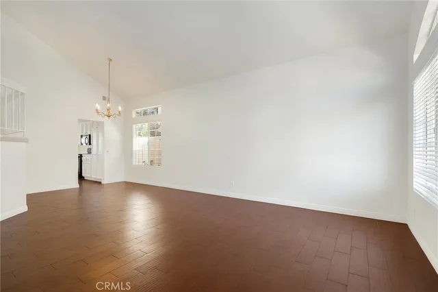 an empty room with windows and chandelier fan