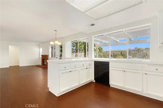 a large white kitchen with granite countertop a stove a sink and a large window