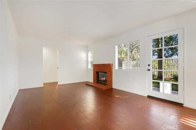 a view of a livingroom with wooden floor and a fireplace